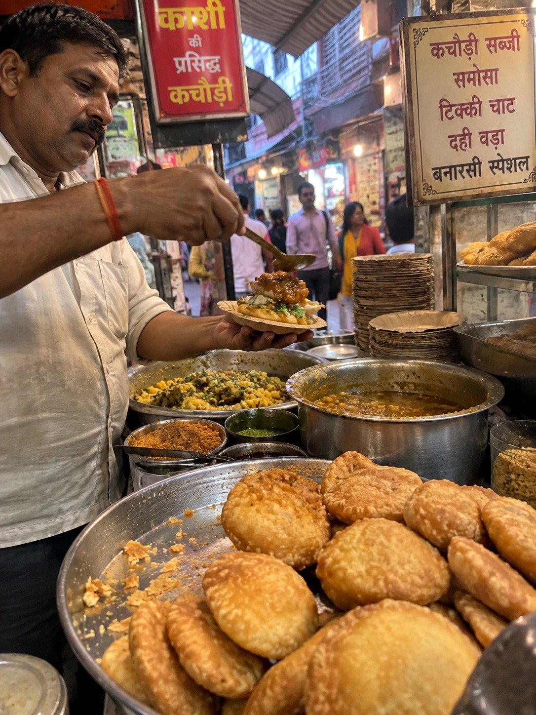 A vendor serving fresh kachori-sabzi at a street food stall in Varanasi